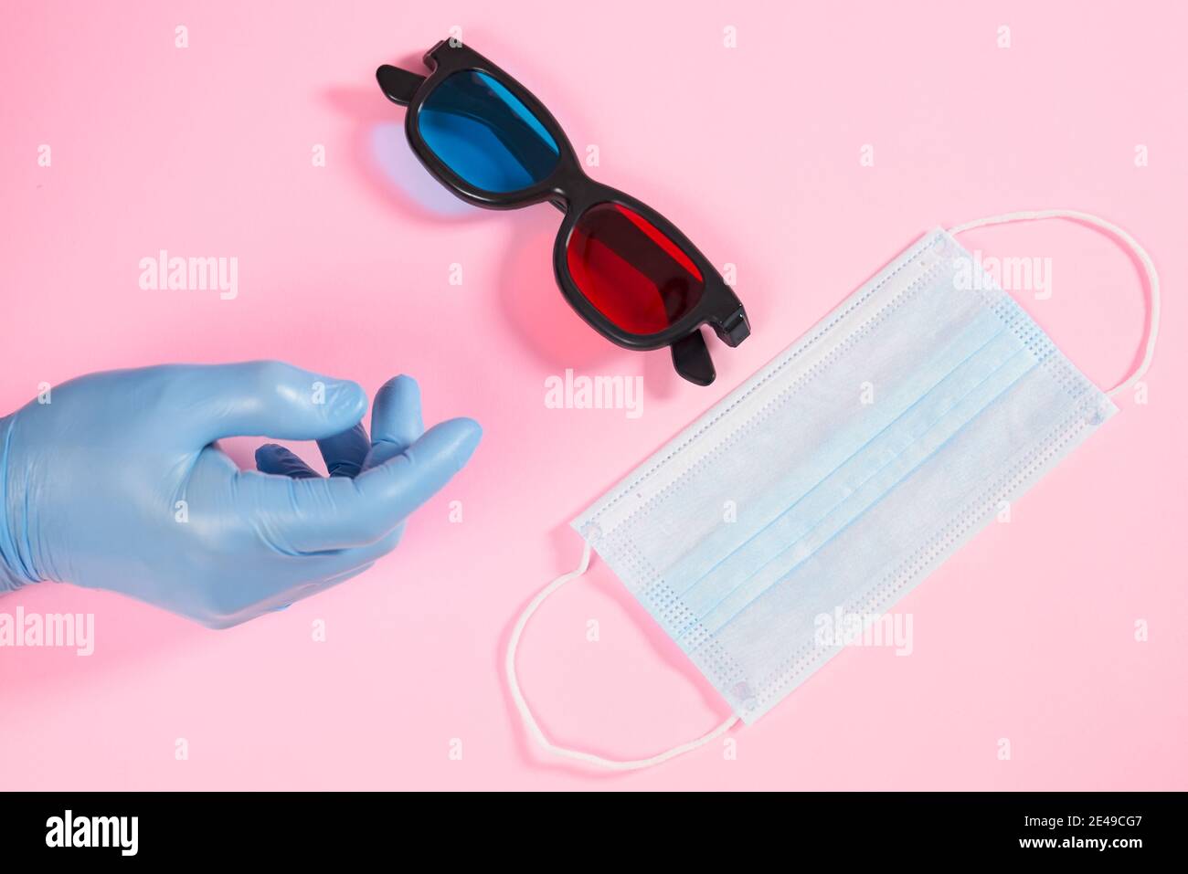Gros plan sur un gant en caoutchouc avec masque de protection et lunettes 3d sur fond rose. Concept de set pour le cinéma. Banque D'Images