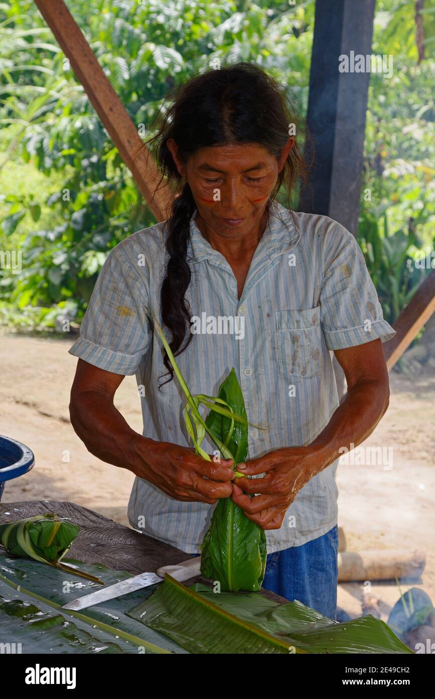 Femme indigène enveloppant la nourriture; feuilles humides; cuisine;  extérieur, travail, transpiration faciale, chaud, humide, blouse colorée,  Amérique du Sud, Amazonie tropicale R Photo Stock - Alamy