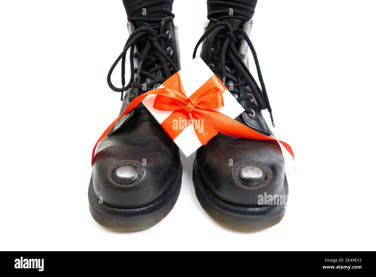 Boîte cadeau blanche avec ruban rouge et noeud sur les bottes en cuir vintage. Concept de cadeau romantique pour la Saint-Valentin. Banque D'Images