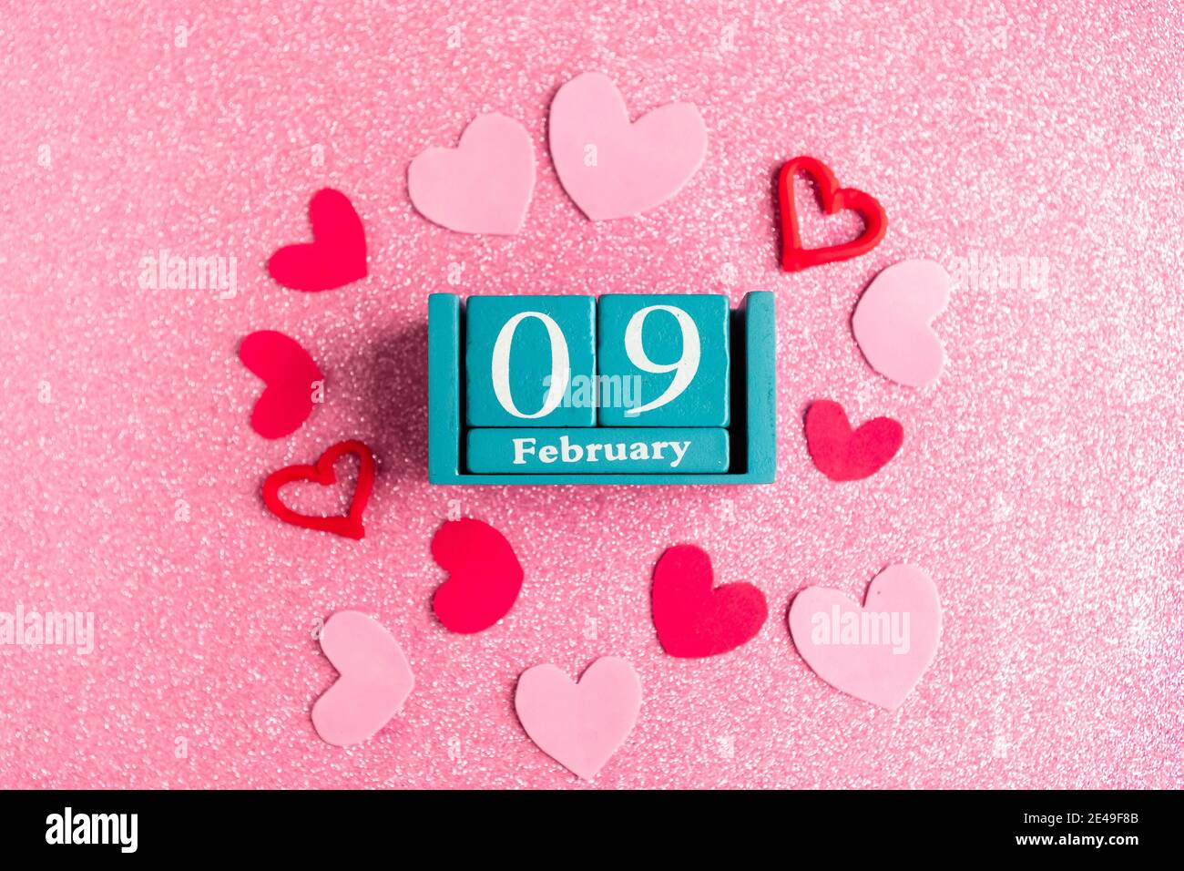 Février 9. Calendrier cube bleu avec mois et date et décorations sur fond rose scintillant. Banque D'Images