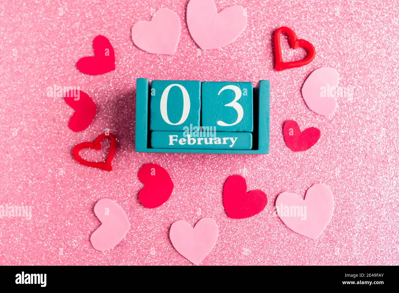Février 3. Calendrier cube bleu avec mois et date et décorations sur fond rose scintillant. Banque D'Images