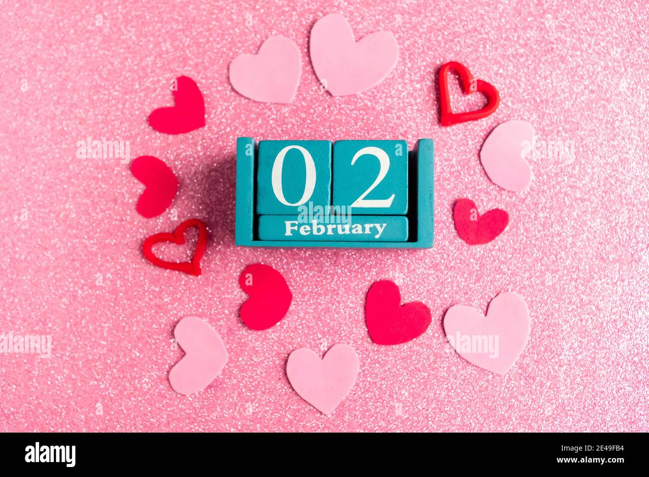Février 2. Calendrier cube bleu avec mois et date et décorations sur fond rose scintillant. Banque D'Images