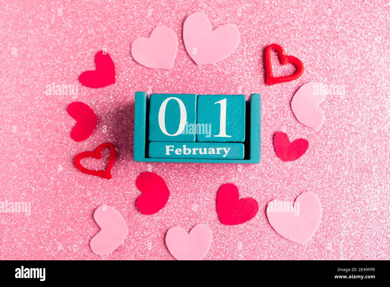 1er février. Calendrier cube bleu avec mois et date et décorations sur fond rose scintillant. Banque D'Images