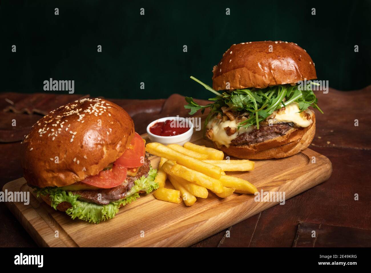 Des hamburgers de bœuf américains frais et délicieux servis avec des frites, un avec des noix frites et du fromage grillé sur une partie décorative en bois de simple Banque D'Images