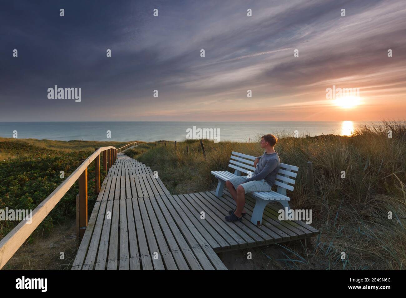 Peu avant le coucher du soleil, une personne est assise sur un banc au passage de la plage à Rantum, sur l'île de Sylt, dans le nord de la Frise, au Schleswig-Holstein, en Allemagne Banque D'Images