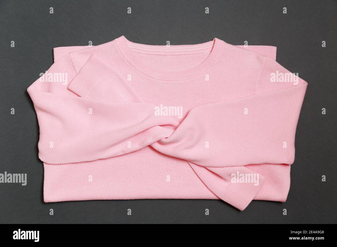 Pull en tricot de couleur rose clair tendance sur un foncé arrière-plan gris avec pose en toile Banque D'Images