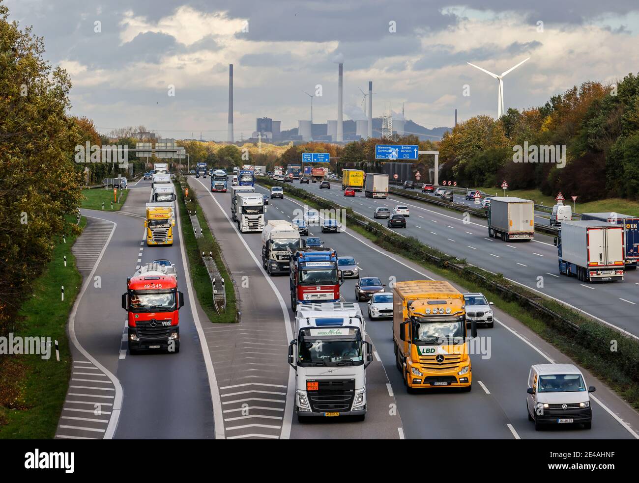 Bottrop, région de la Ruhr, Rhénanie-du-Nord-Westphalie, Allemagne - de nombreux camions conduisent sur l'autoroute A2, à l'arrière de la centrale électrique au charbon de Gelsenkirchen Scholven, à droite une éolienne, industrie et trafic dans la région de la Ruhr. Banque D'Images