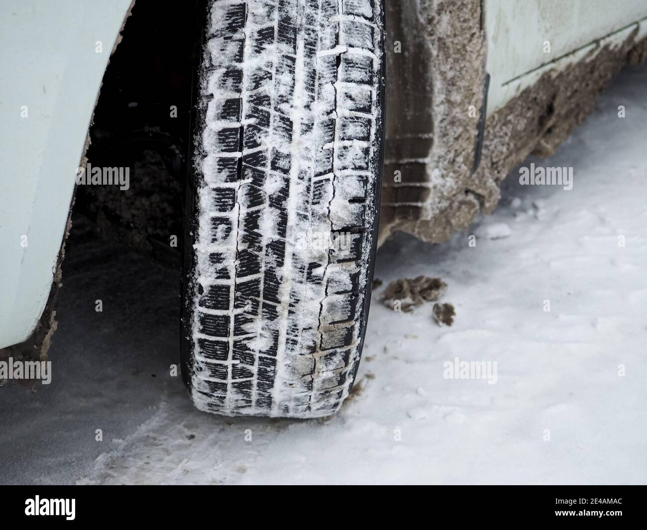 Gros plan de la bande de roulement d'un pneu de voiture d'hiver avec de la  neige et de la glace. L'utilisation de pneus spéciaux en hiver est la base d'un  freinage et