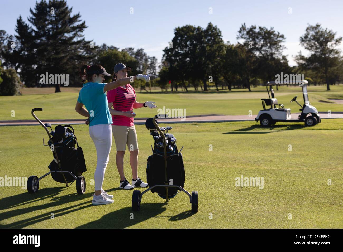 Deux femmes caucasiennes avec des sacs de golf debout sur le terrain de golf parler Banque D'Images