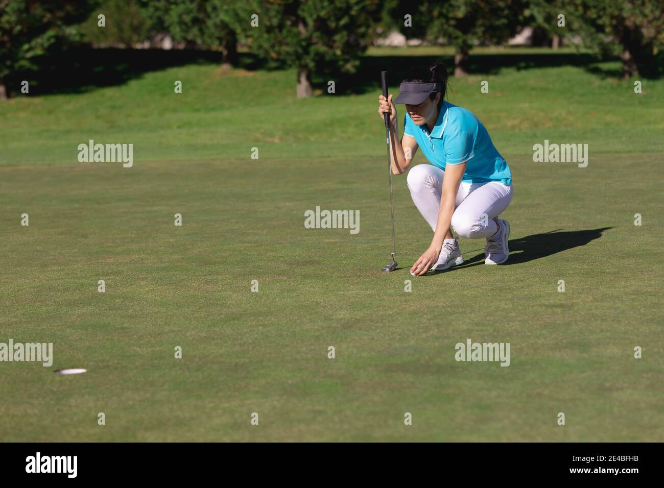 Femme caucasienne jouant au golf plaçant le ballon avant de prendre le tir à trou Banque D'Images