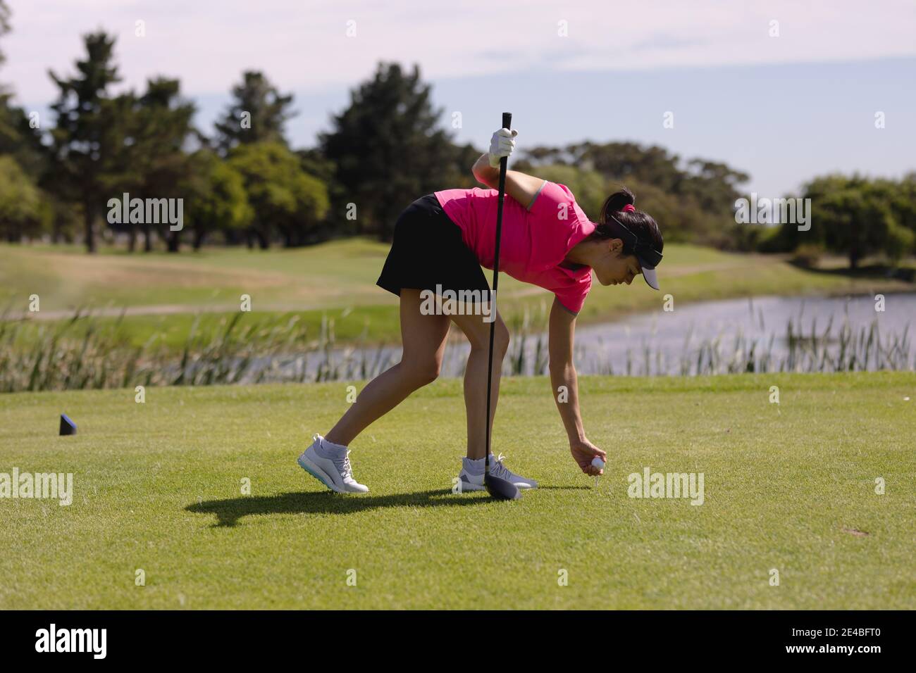 Femme caucasienne jouant au golf penchée pour placer le ballon avant de prendre une prise de vue Banque D'Images