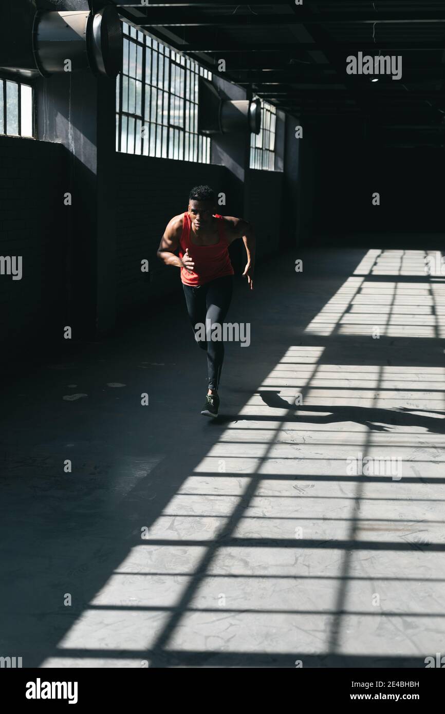 Homme afro-américain portant des vêtements de sport jogging dans des villes vides bâtiment Banque D'Images