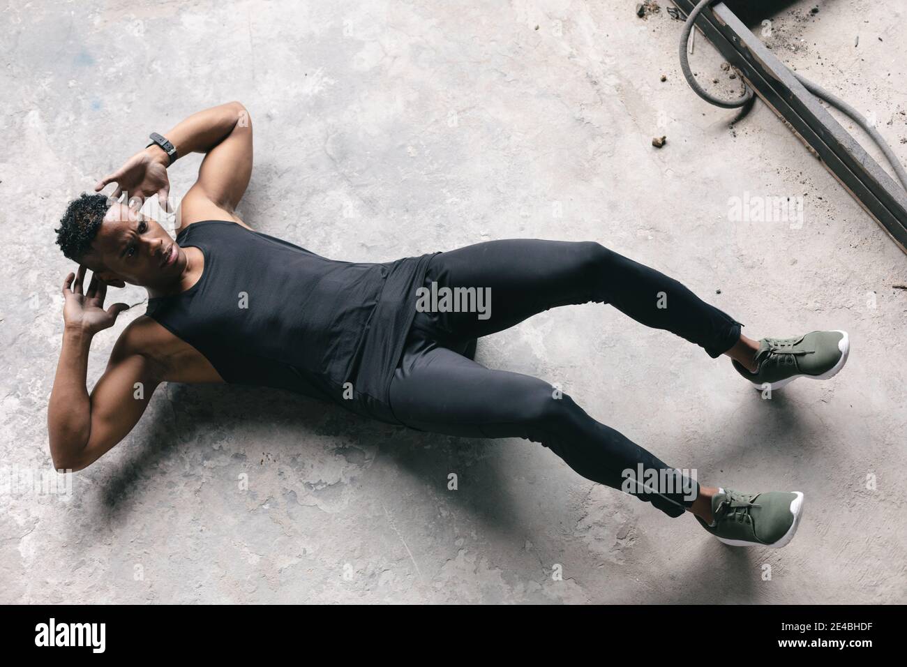 Homme afro-américain portant des vêtements de sport s'exerçant à craquer bâtiment urbain vide Banque D'Images