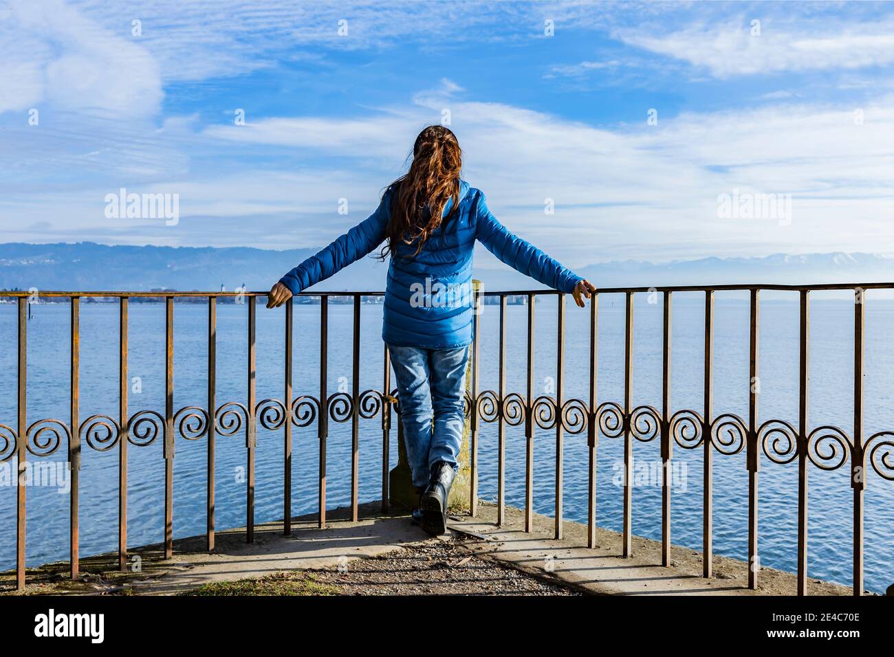 Femme dans une veste de duvet bleue sur la main par un lac Banque D'Images