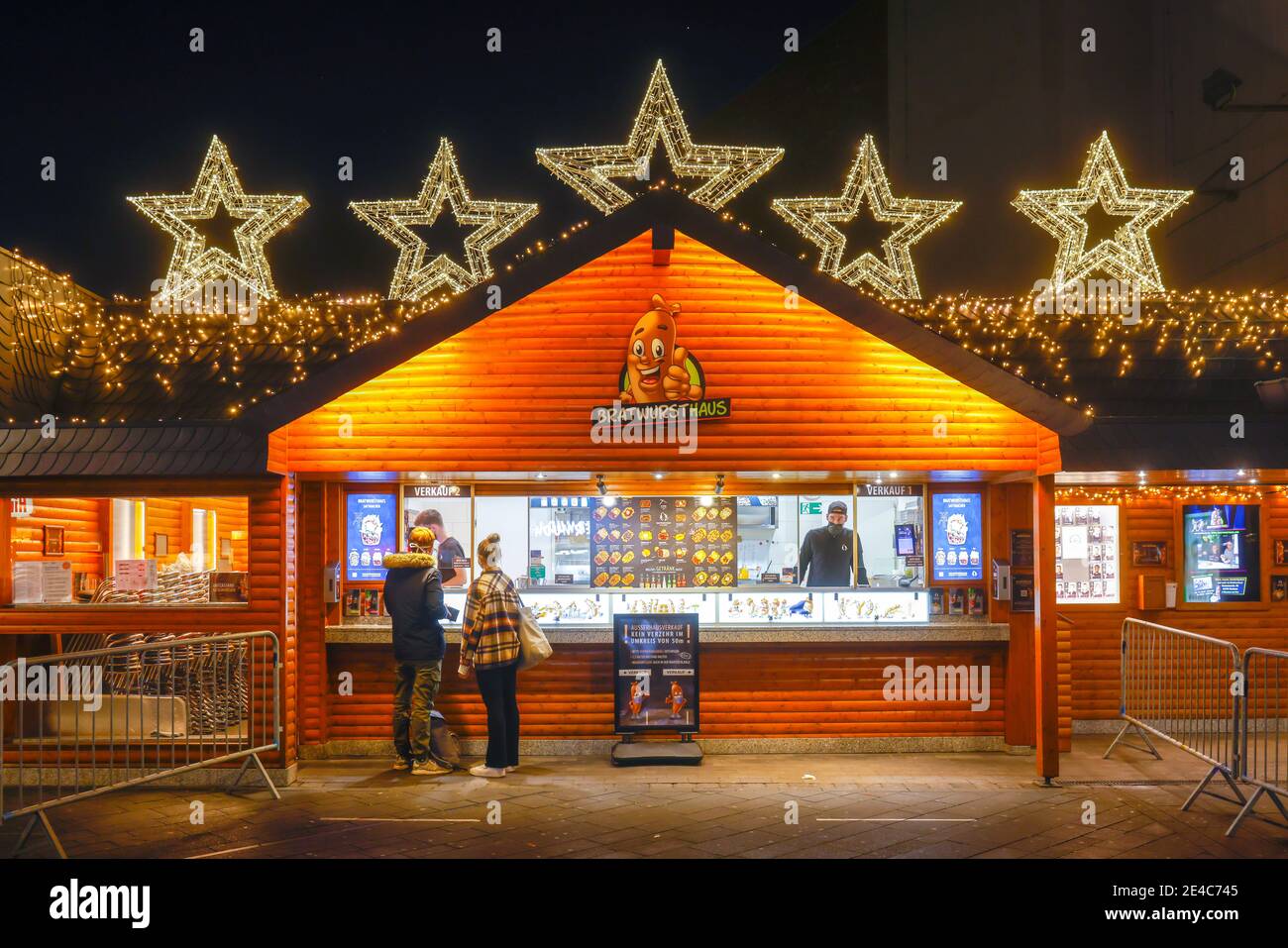 Bochum, région de la Ruhr, Rhénanie-du-Nord-Westphalie, Allemagne - Bratwursthaus, le snack-bar le plus populaire de Bochum au Triangle des Bermudes dans le centre-ville de Bochum en temps de crise de la corona pendant la deuxième partie du confinement, passe-près avec des masques protecteurs sur la Kortumstrasse décorée de Noël, la principale rue commerçante de la zone piétonne. Banque D'Images