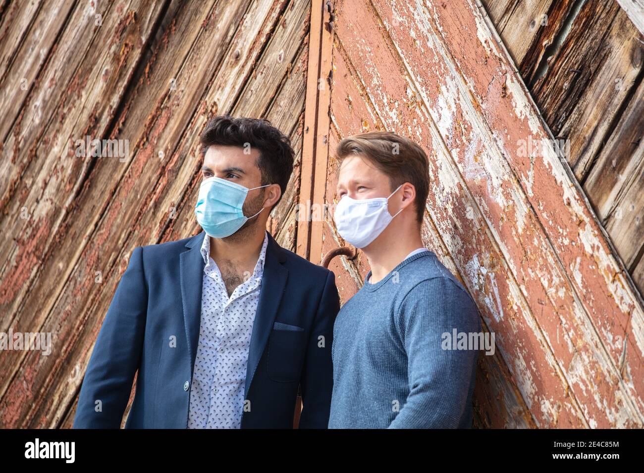 Groupe de jeunes, temps libre dans la ville. Debout à l'extérieur. Deux personnes se rencontrent, sans distance, en portant un masque dans l'espace public. Exigence de masque. Banque D'Images