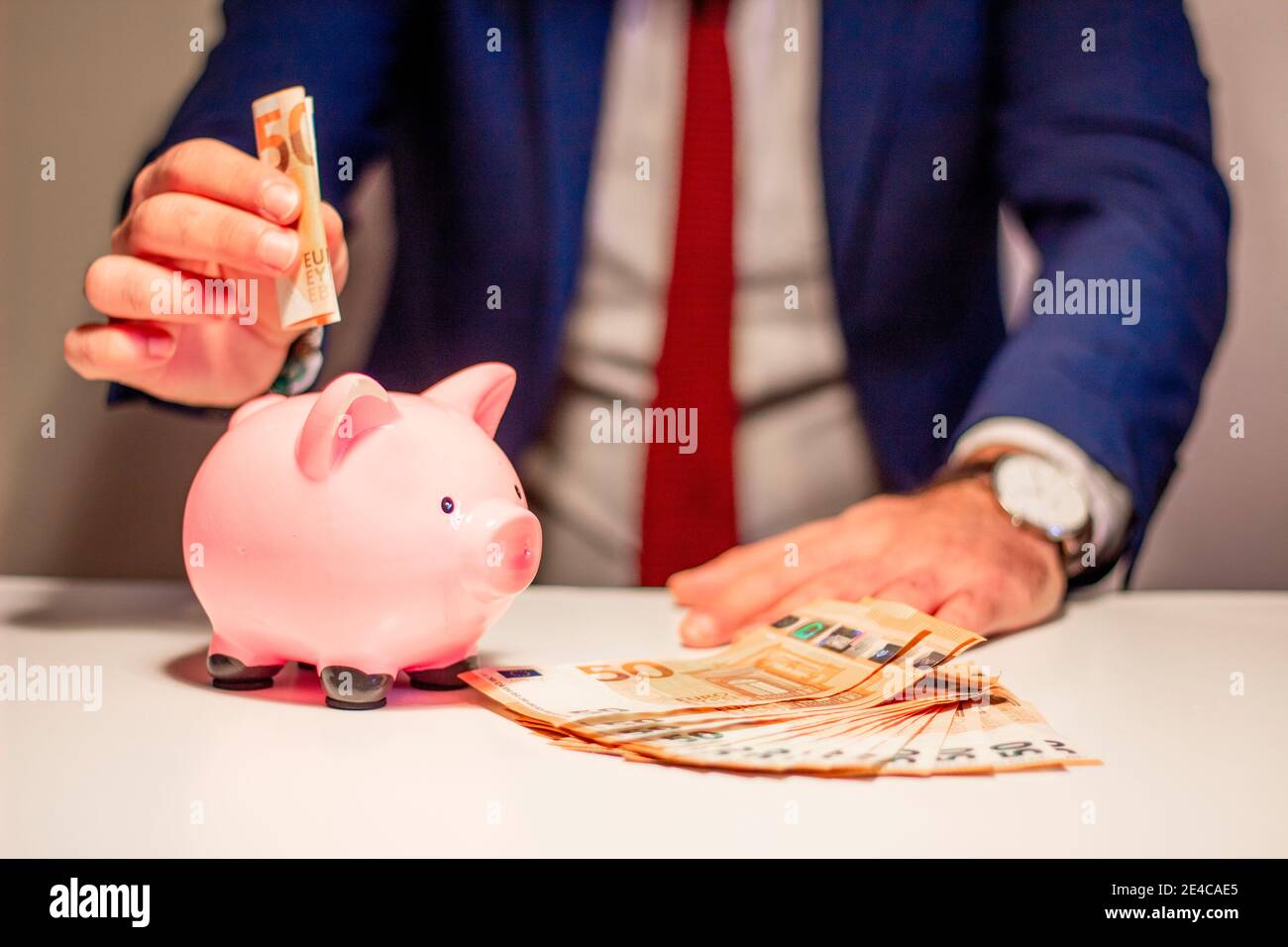 Homme d'affaires mettant cinquante euros d'argent de billet de banque dans la piggy banque. Concept financier et économique Banque D'Images