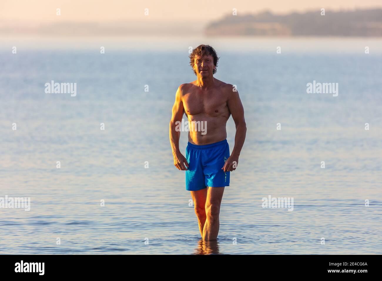 Homme en forme à cinquante plus tôt le matin dans la mer. Demain, l'homme est debout dans la mer Baltique sur la plage de Scharbeutz. Banque D'Images