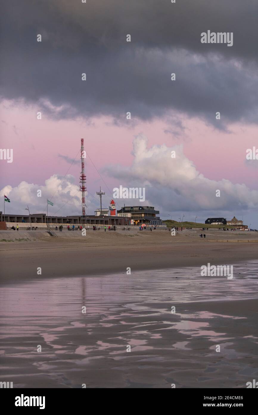 Europe, Allemagne, Basse-Saxe, Mer du Nord, Iles de Frise orientale, Parc National de la Mer des Wadden, Borkum, coucher de soleil sur la plage avec un ciel rose, marcheurs et cyclistes sur la promenade de la plage Banque D'Images