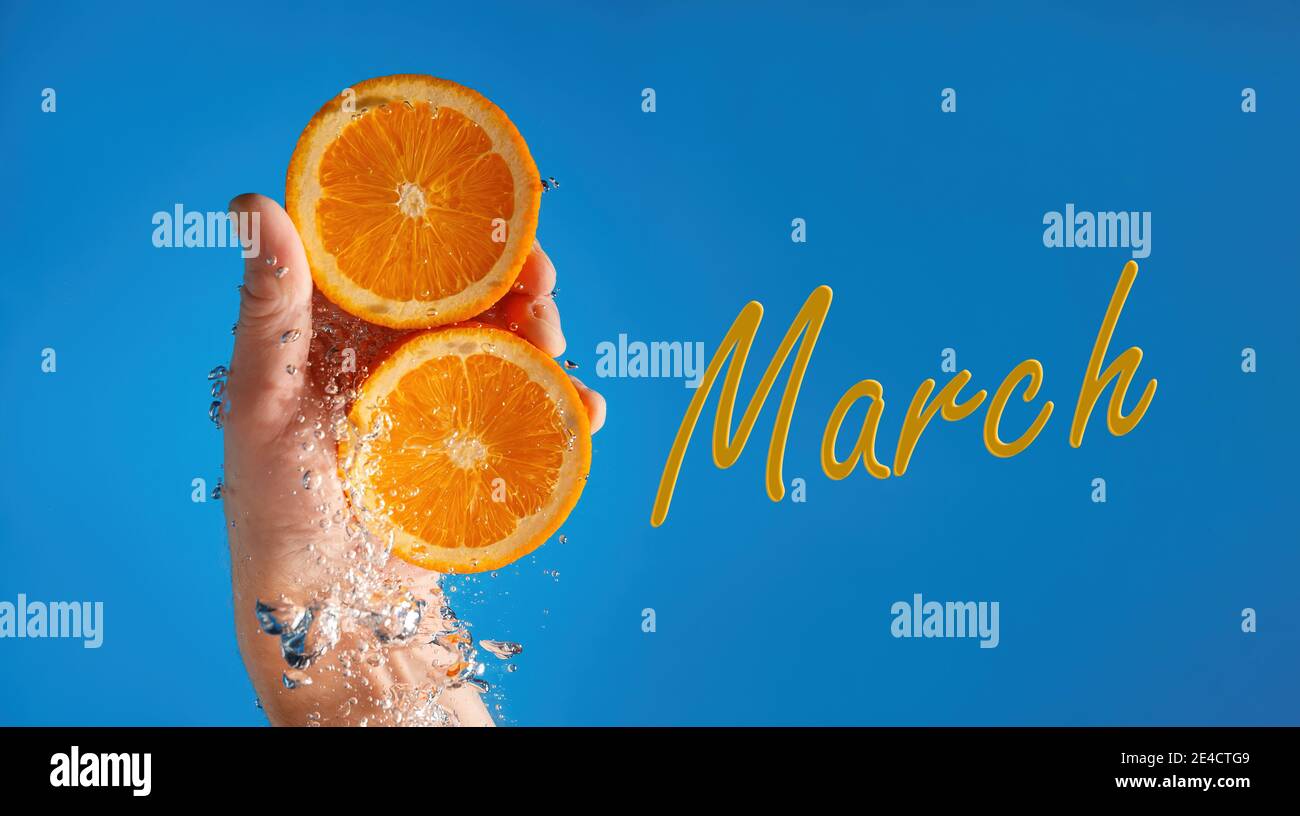 La main d'un homme tient deux moitiés d'une orange dans l'eau, formant le nombre 8. Contexte de la fête de la femme, 8 mars. Banque D'Images
