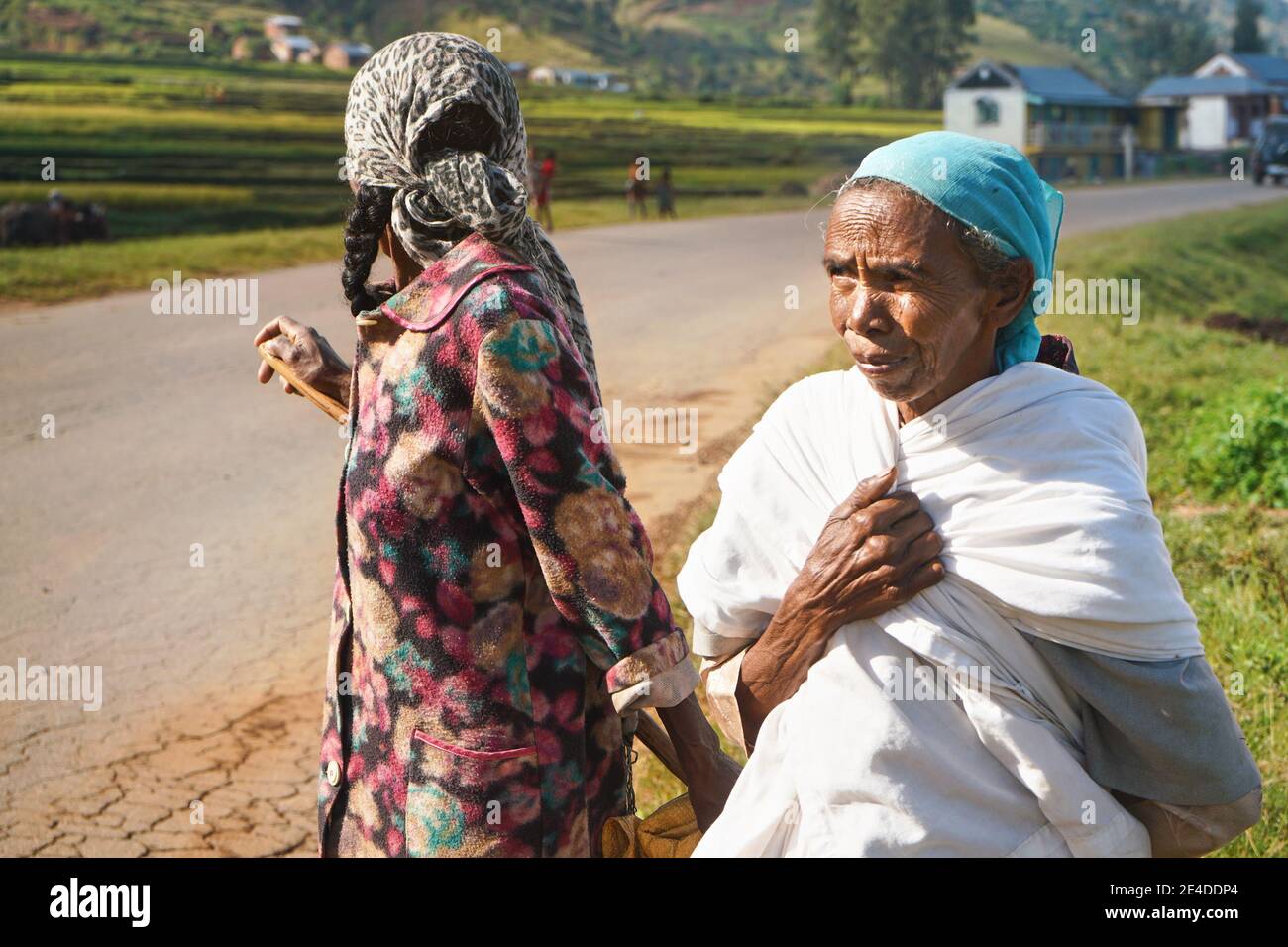 Manandoana, Madagascar - 26 avril 2019 : deux femmes malgaches âgées debout à côté du champ de riz où elles ont travaillé le jour ensoleillé, une en regardant en arrière. Péopl Banque D'Images