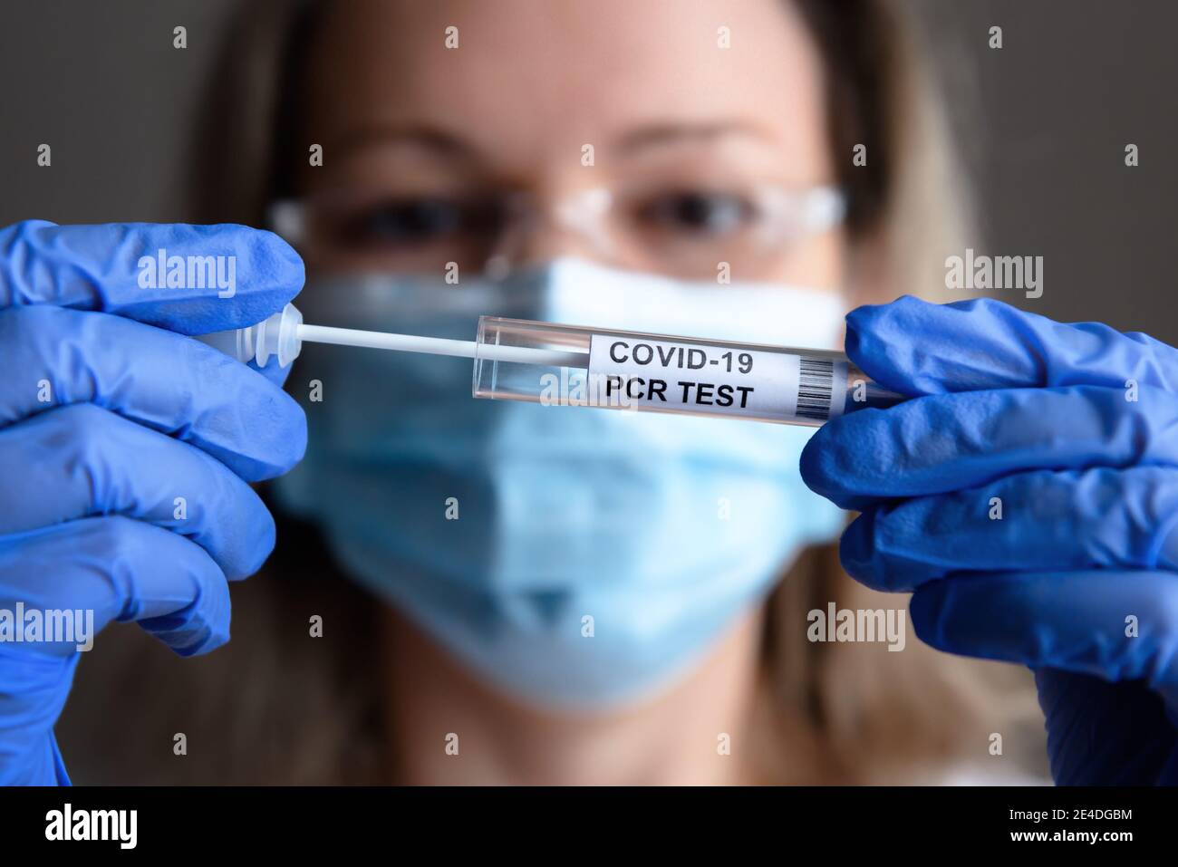 Test COVID-19 dans les mains du médecin en gros plan, la femme en masque médical tient la trousse de prélèvement de l'écouvillon du coronavirus en laboratoire. Concept de diagnostic de virus corona Banque D'Images