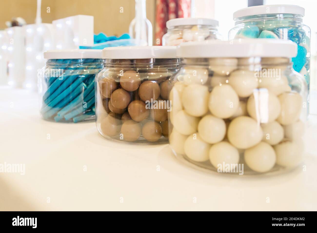 Bocaux en verre avec bonbons et chocolats, bleu, brun et blanc, sur une table lors d'une fête. Banque D'Images