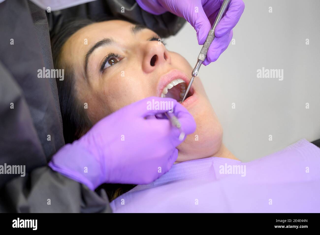 Une jeune femme visite la clinique de dentisterie pour un traitement dentaire professionnel. Femme dentiste se plie au-dessus du patient. Outil d'examen par le médecin pour examen oral. Photo de haute qualité Banque D'Images