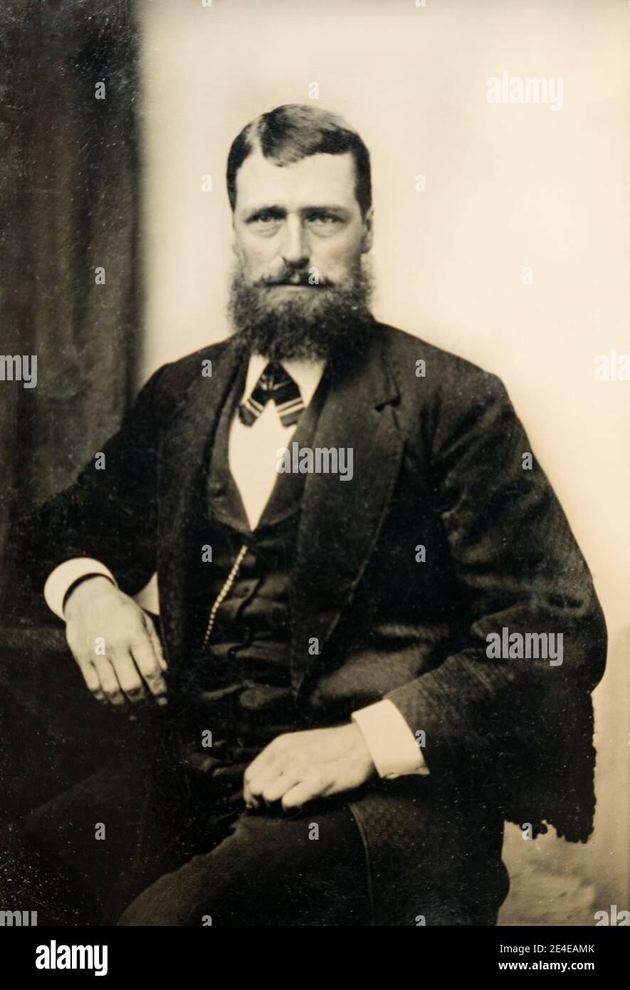 American archive portrait monochrome sur une plaque de type-type d'un homme avec une barbe portant un costume et une chaîne de montre de poche avec une teinte peinte à la main retouchée. Prise fin XIXe siècle, NY, États-Unis Banque D'Images