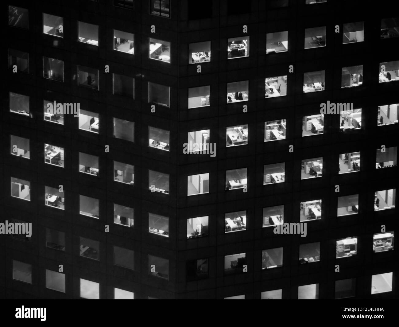 image monochrome des fenêtres éclairées d'un grand immeuble de bureaux la nuit Banque D'Images