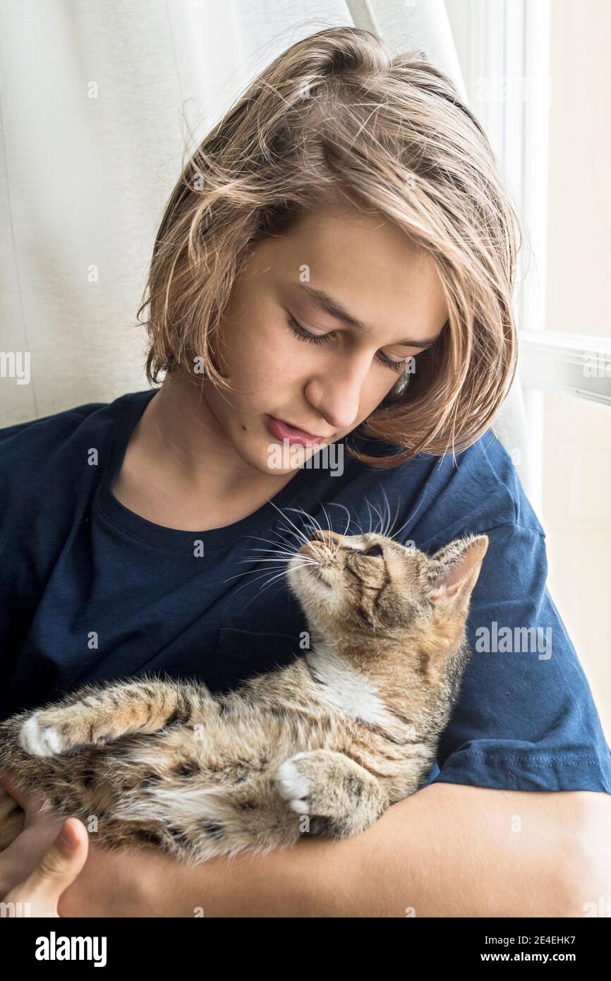 le garçon blond de l'adolescence tient le chaton domestique à la maison Banque D'Images