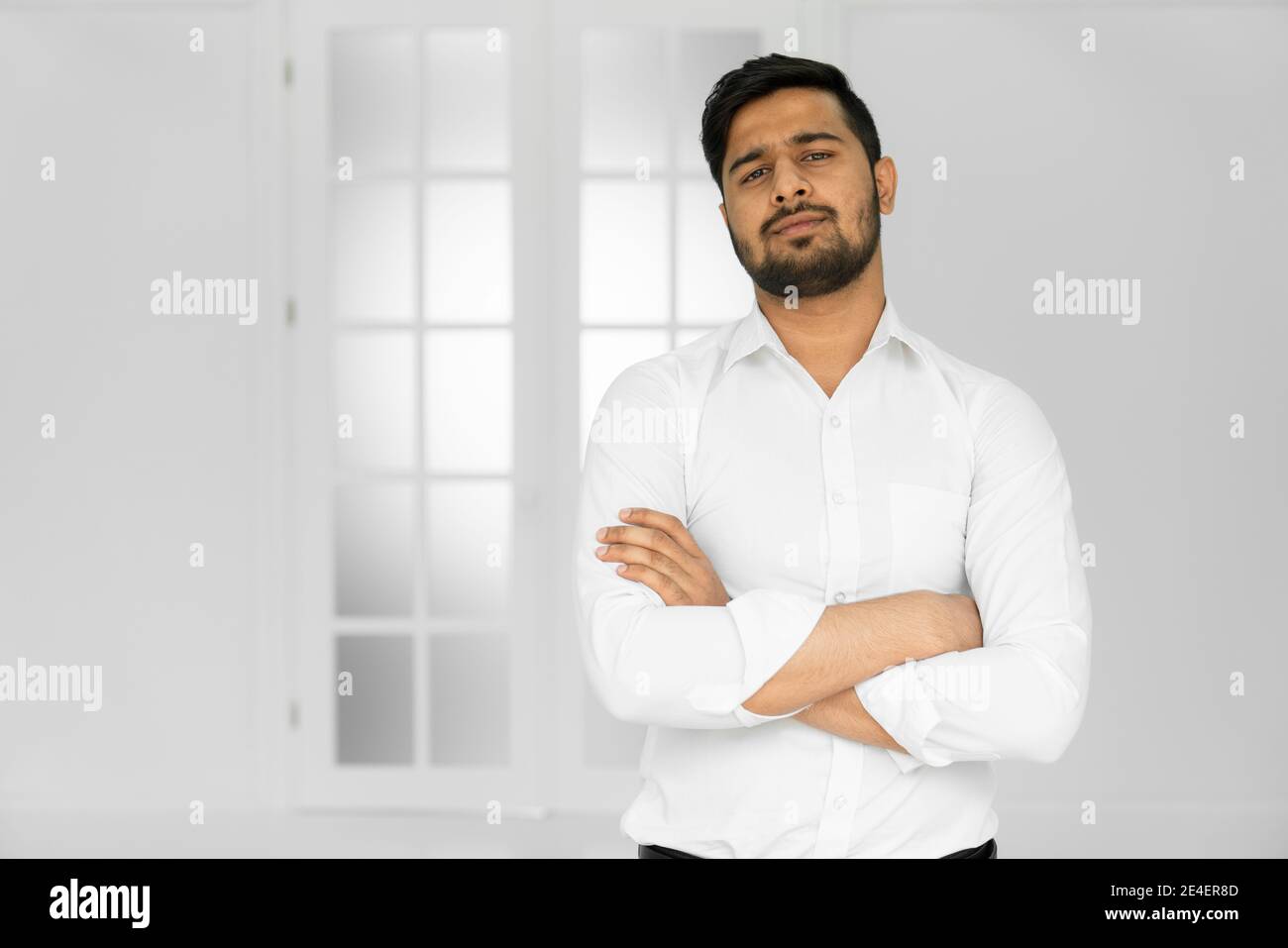 Jeune homme indien beau en chemise blanche debout avec les mains plié sur  fond blanc Photo Stock - Alamy