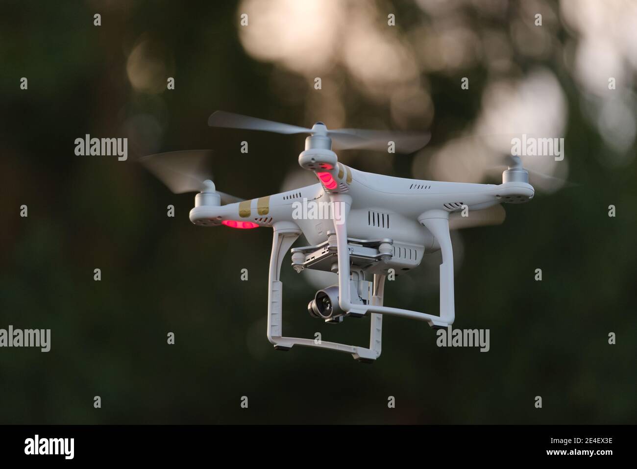 14 - drone blanc transportant une caméra sur une nacelle regarde à gauche. Beaucoup d'espace de copie grâce à la mise au point sélective et à l'arrière-plan sombre. Banque D'Images