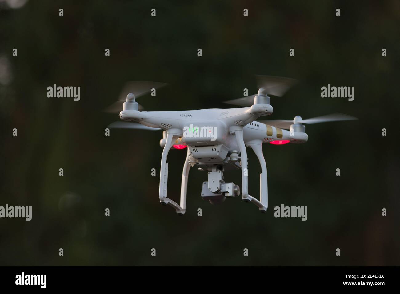 24 - drone vidéo de surveillance quadcopter blanc avec arrière-plan sombre. Le sujet isolé utilisant une mise au point sélective se distingue également par la couleur de la lumière. Banque D'Images