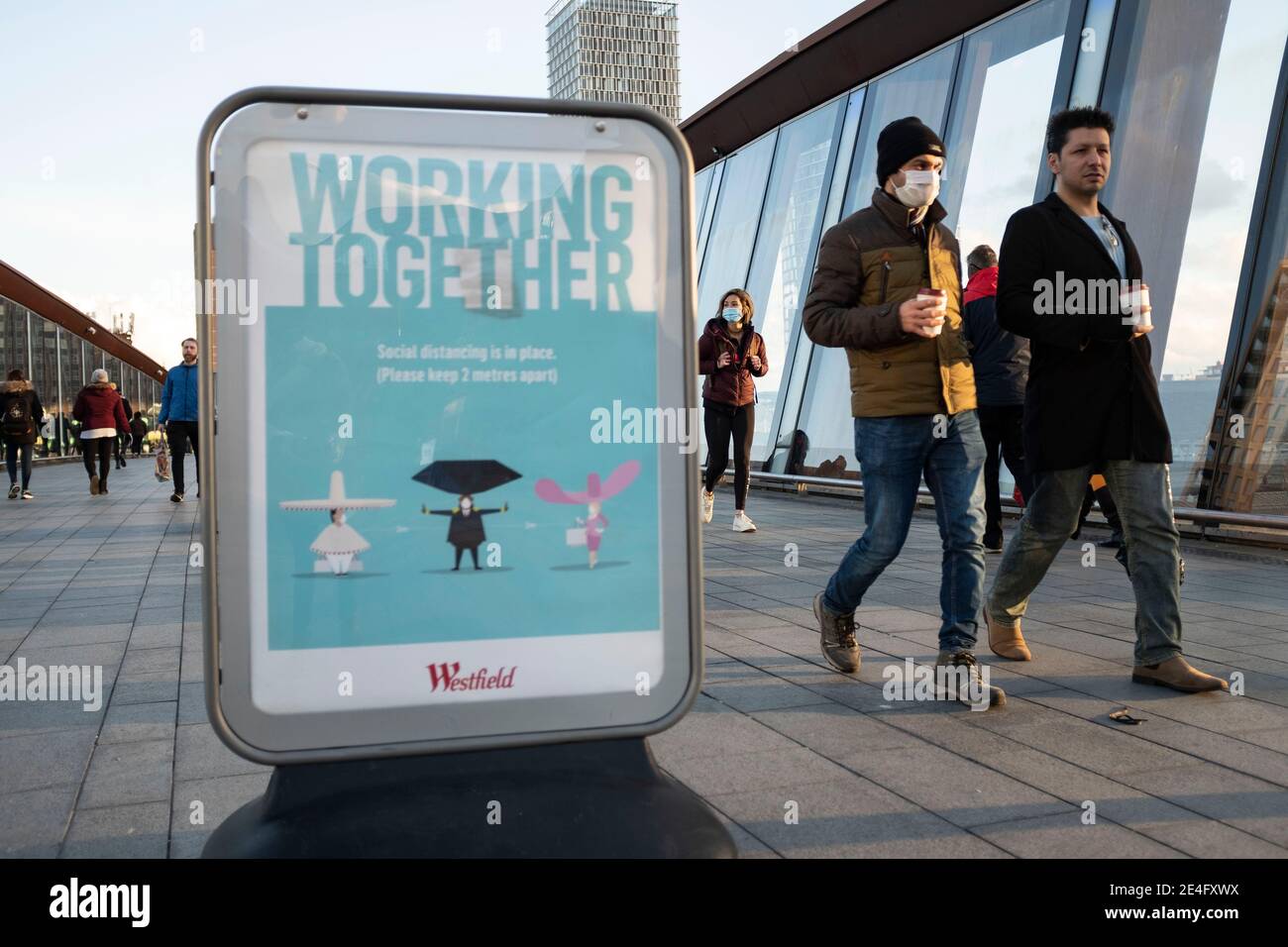 Londres, Royaume-Uni. 23 janvier 2021. Les personnes qui passent un panneau COVID ont lu « travailler ensemble, prendre des distances sociales en place, s'il vous plaît garder 2 mètres à l'écart » à Stratford, le London Borough of Newham, Angleterre, Royaume-Uni le 23 janvier 2021. Certains des sites Covid d'Angleterre sont encore à Londres Hounslow, Ealing, Brent, Barking et Dagenham et Newham sont les bourgs qui tombent dans le top 10 du pays pour les taux les plus mauvais cas. Crédit : May James/ZUMA Wire/Alay Live News Banque D'Images