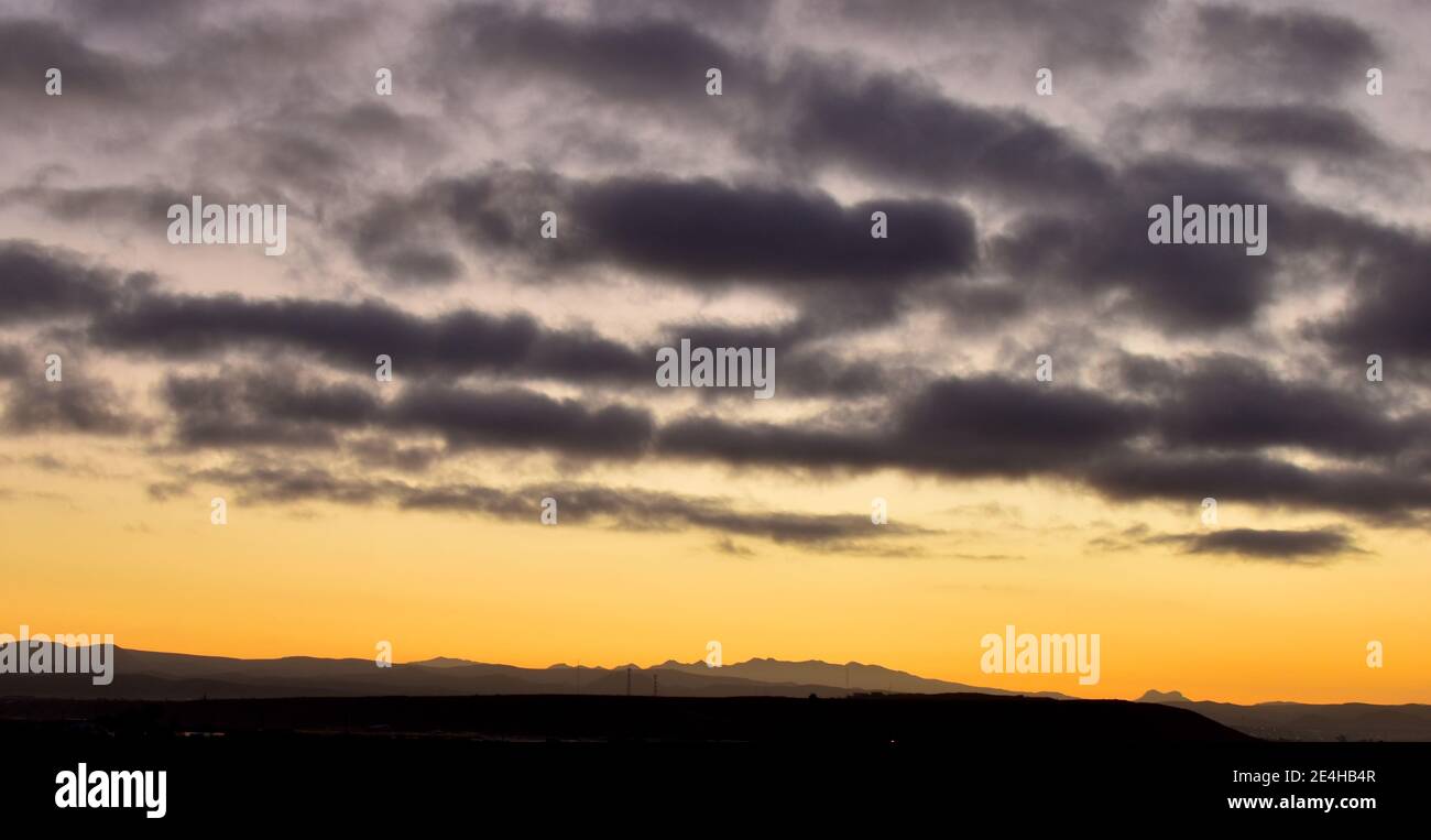 Un ciel nuageux brille en jaune et orange à l'horizon au lever du soleil près de San Quintin, Baja California, Mexique Banque D'Images