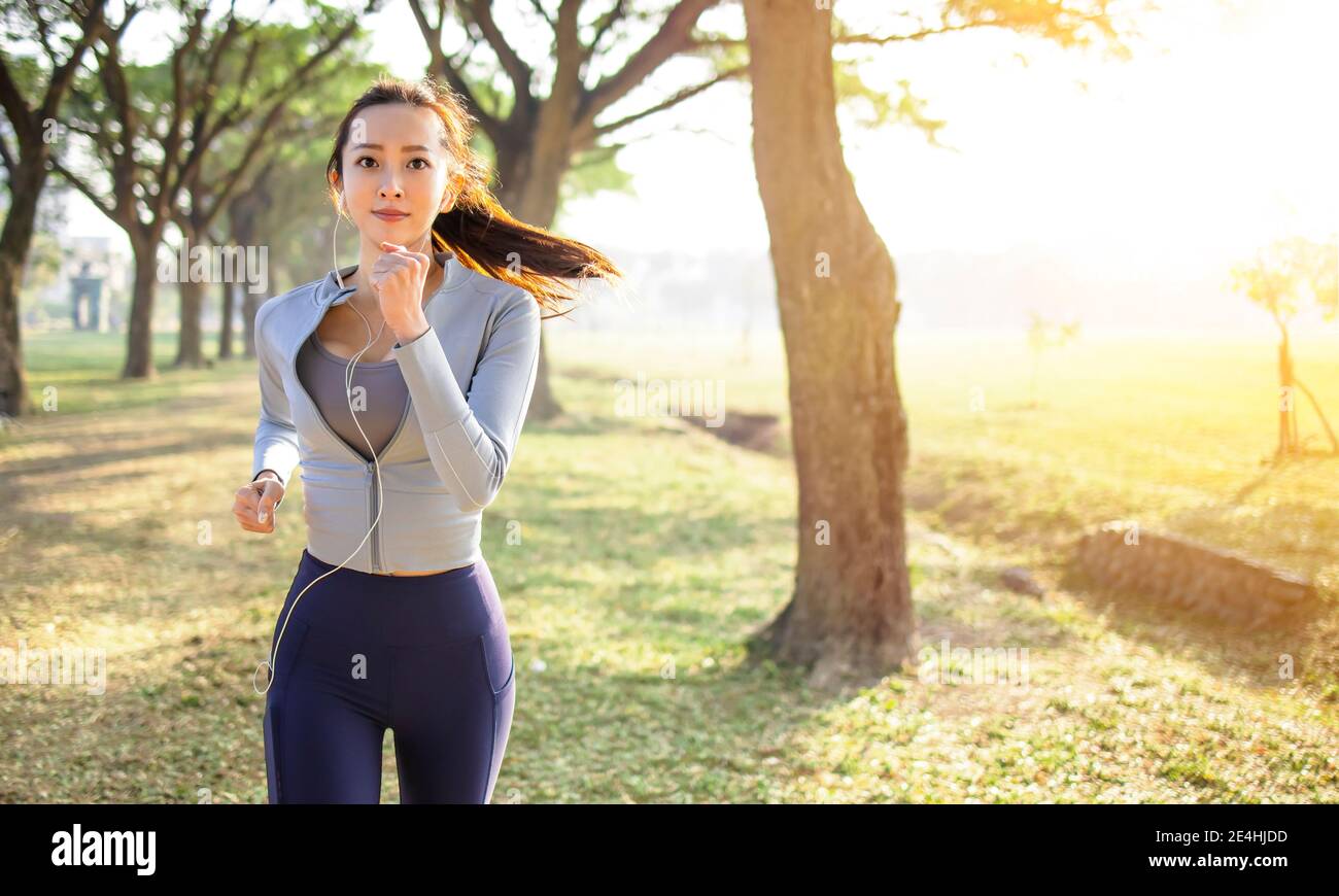 belle jeune femme asiatique courant dans le parc le matin Banque D'Images