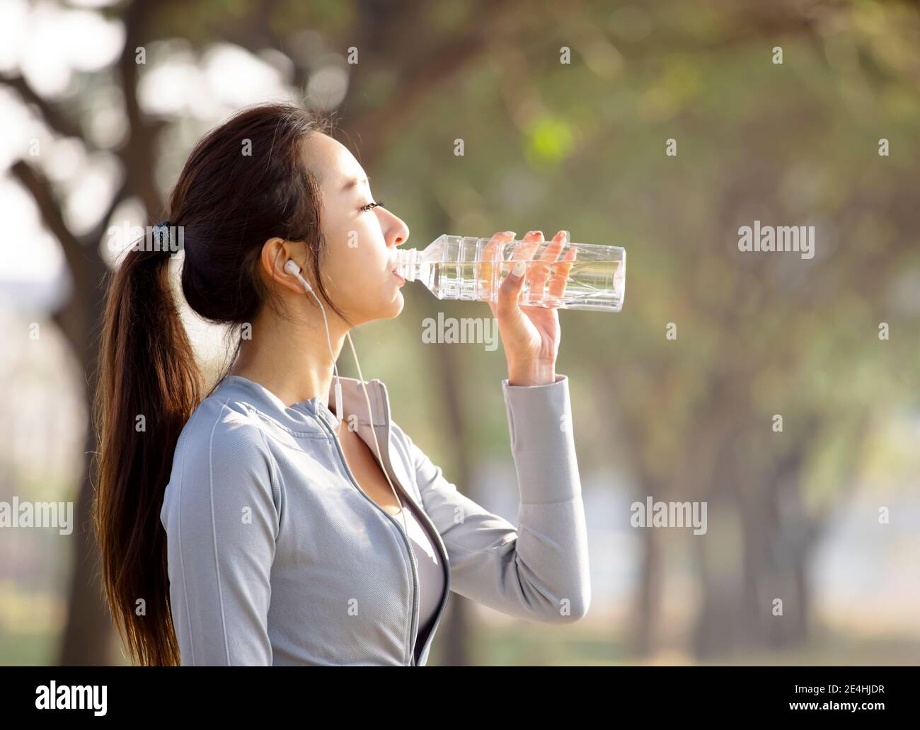 Jeune femme à boire de l'eau après le jogging Banque D'Images