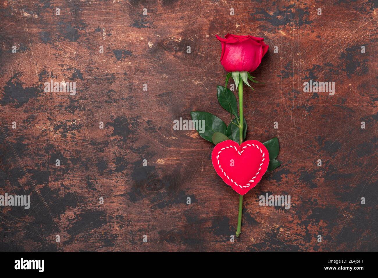 Carte de vœux de Saint-Valentin avec rose rouge et coeur en tissu décoratif sur fond de bois. Vue de dessus. Espace de copie - image Banque D'Images