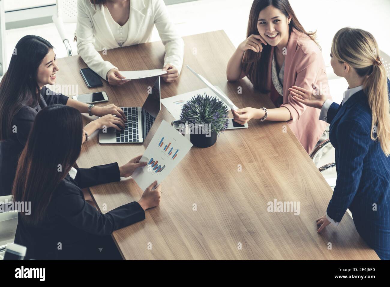 Femme d'affaires dans la discussion de réunion de groupe avec d'autres femmes d'affaires collègues dans bureau moderne avec ordinateur portable et documents sur table Banque D'Images