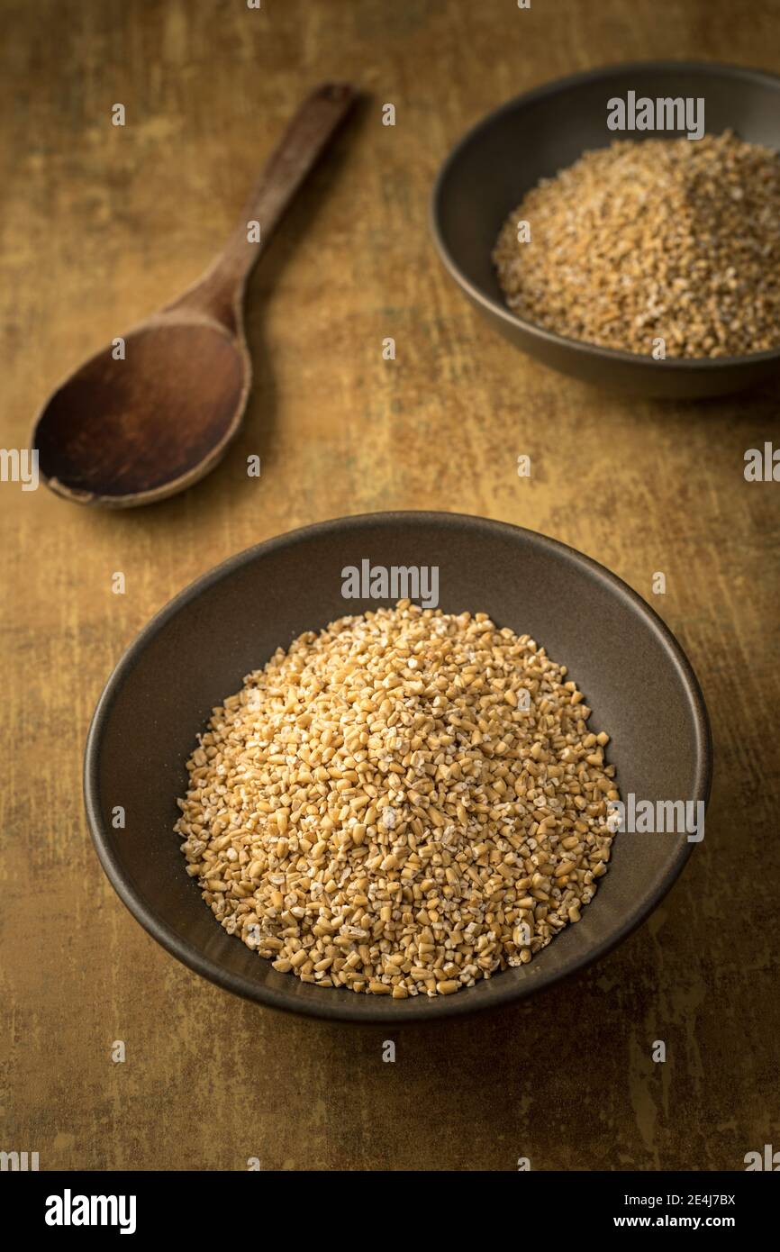 Un gros plan d'un bol d'avoine coupée en acier séché dans un bol et une cuillère en bois. Banque D'Images