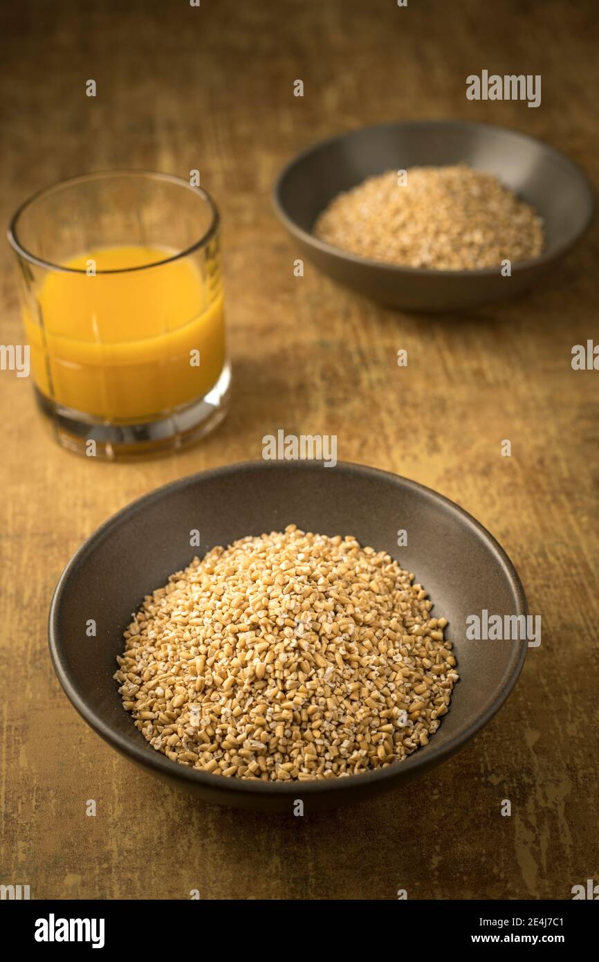 Un gros plan d'un bol d'avoine coupée en acier séché dans un bol et d'un verre de jus d'orange. Banque D'Images