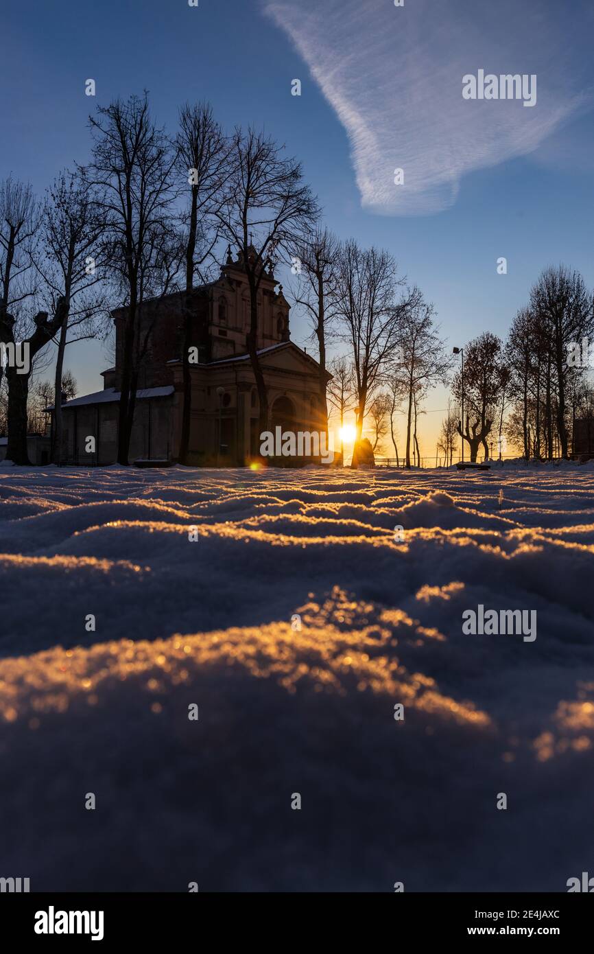 Soleil levant au-dessus de la plaine enneigée et du sanctuaire de Varalino di Galliate, Novara, Piémont, Italie Banque D'Images