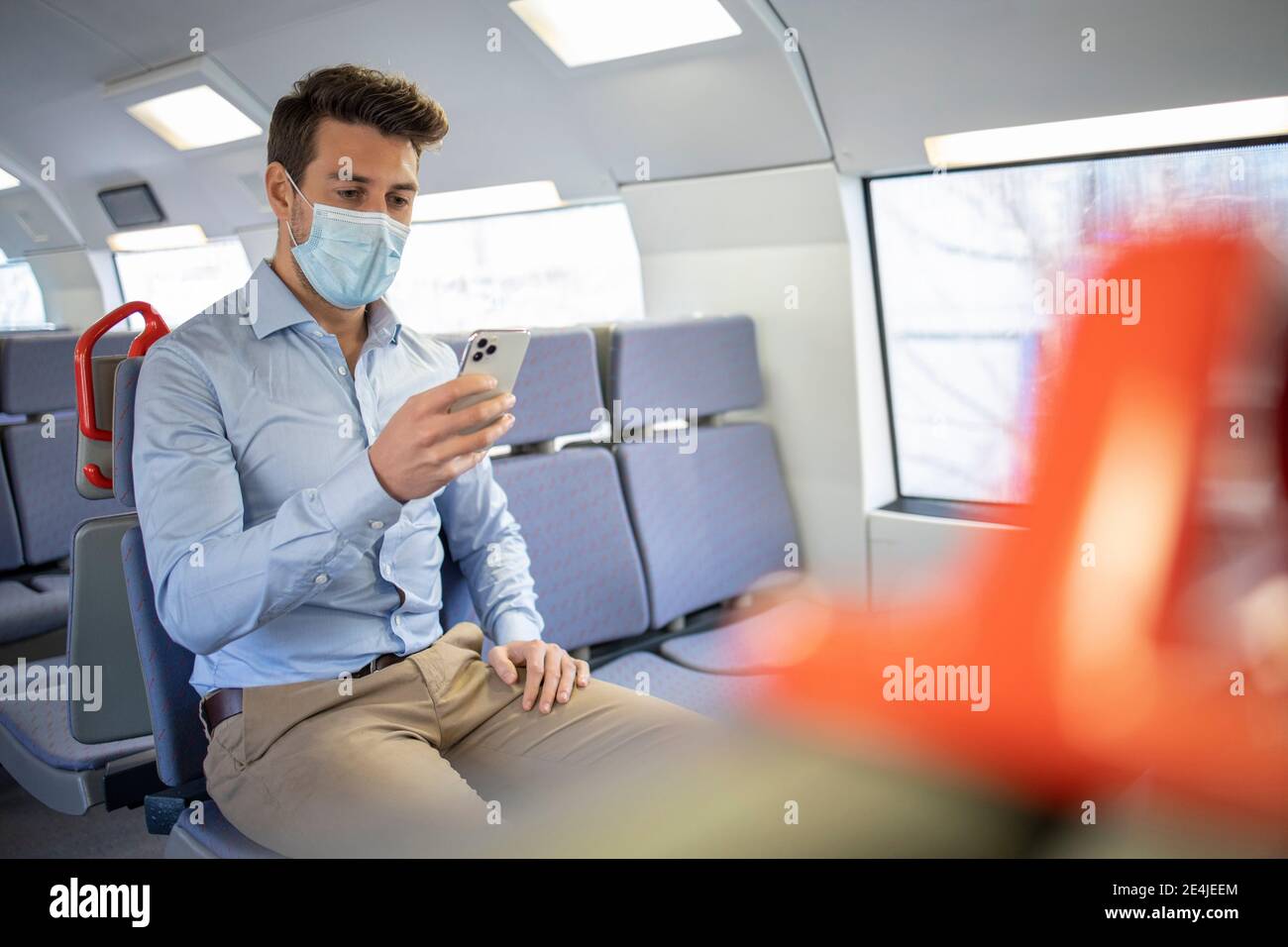 Homme d'affaires portant un masque facial attendant le train tout en se tenant à la plate-forme Banque D'Images