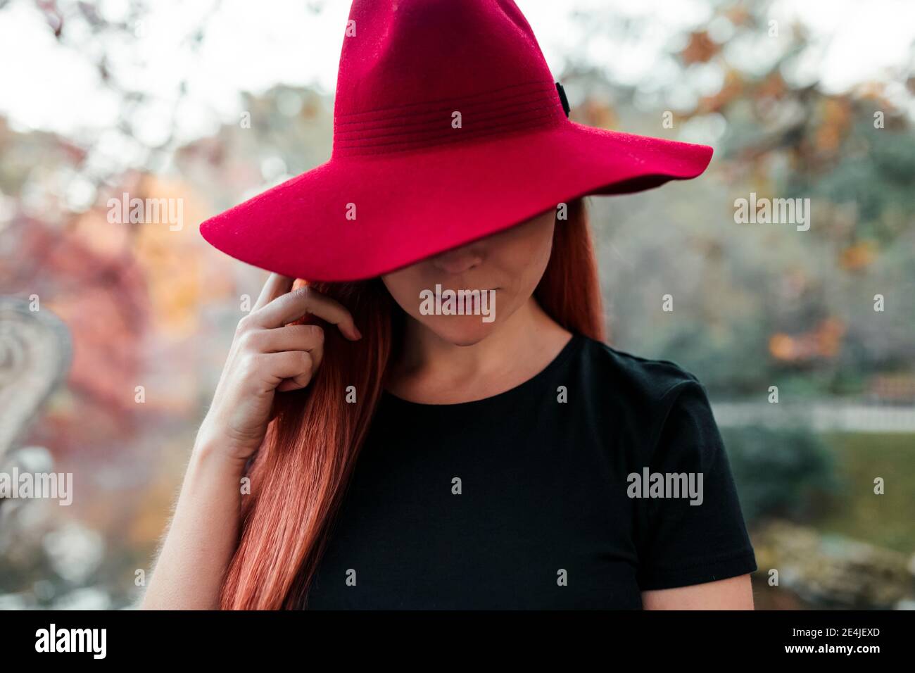 Gros plan d'une femme adulte de taille moyenne portant un chapeau rouge dans le parc Banque D'Images