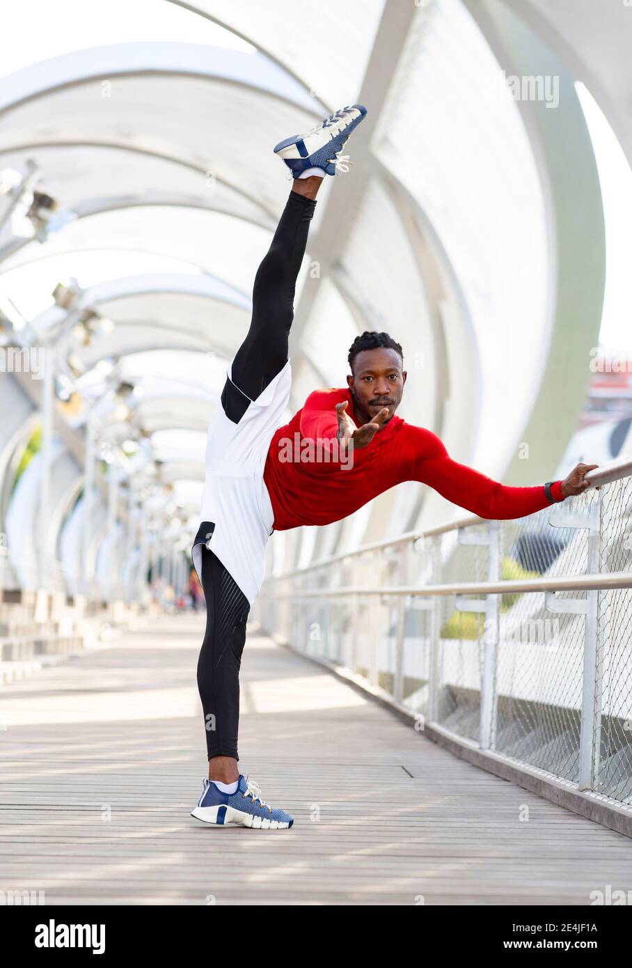 Sportsman s'étirant tout en faisant des fentes debout sur la passerelle Banque D'Images