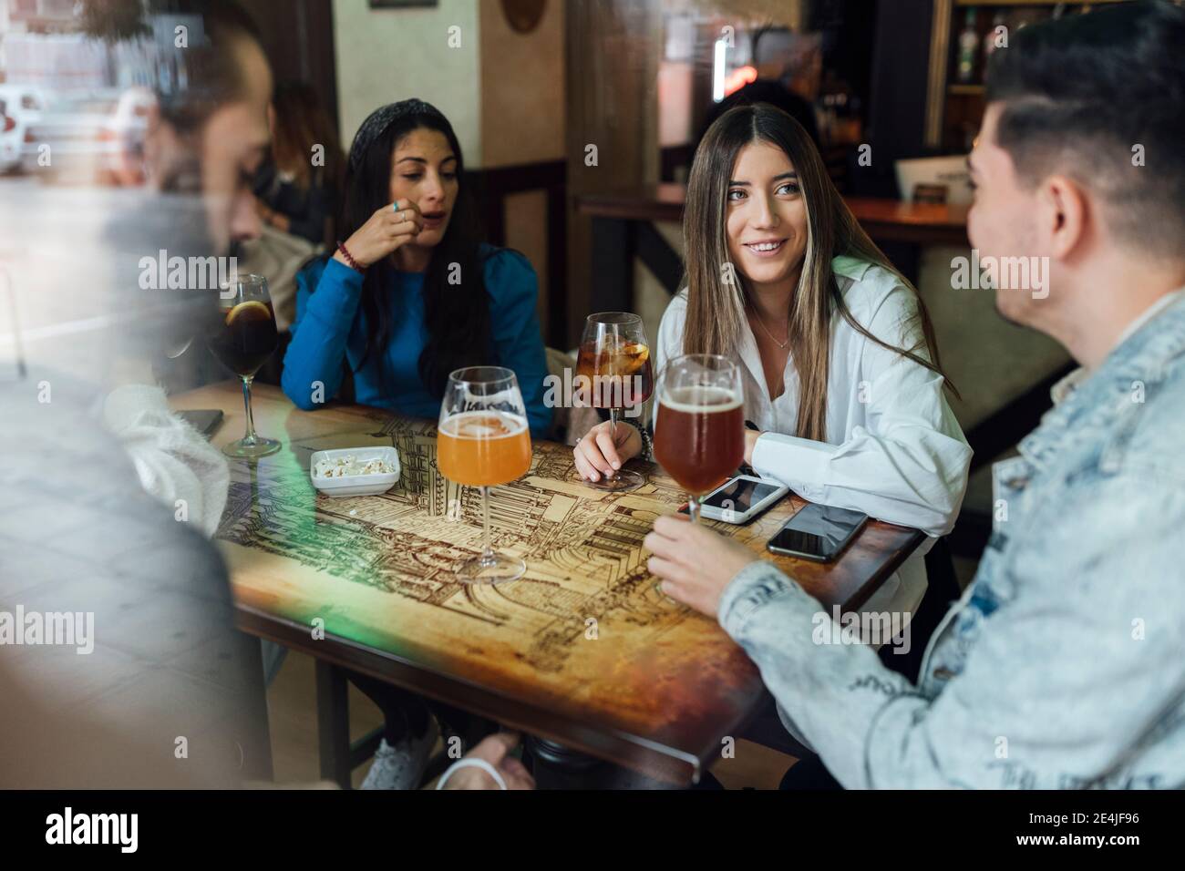 Des amis hommes et femmes parlent tout en prenant un verre au restaurant Banque D'Images