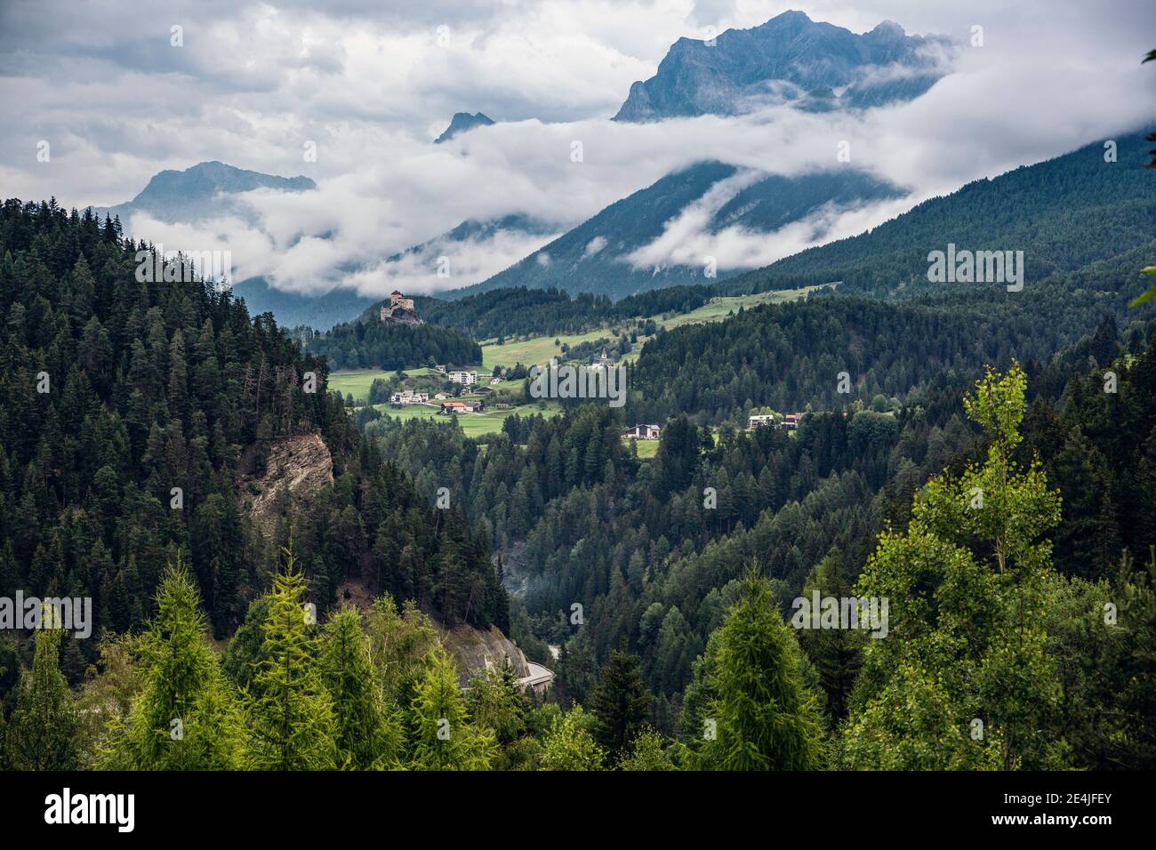 Suisse, canton des Grisons, Scuol, Vallée verte boisée avec le château de Tarasp en arrière-plan éloigné Banque D'Images