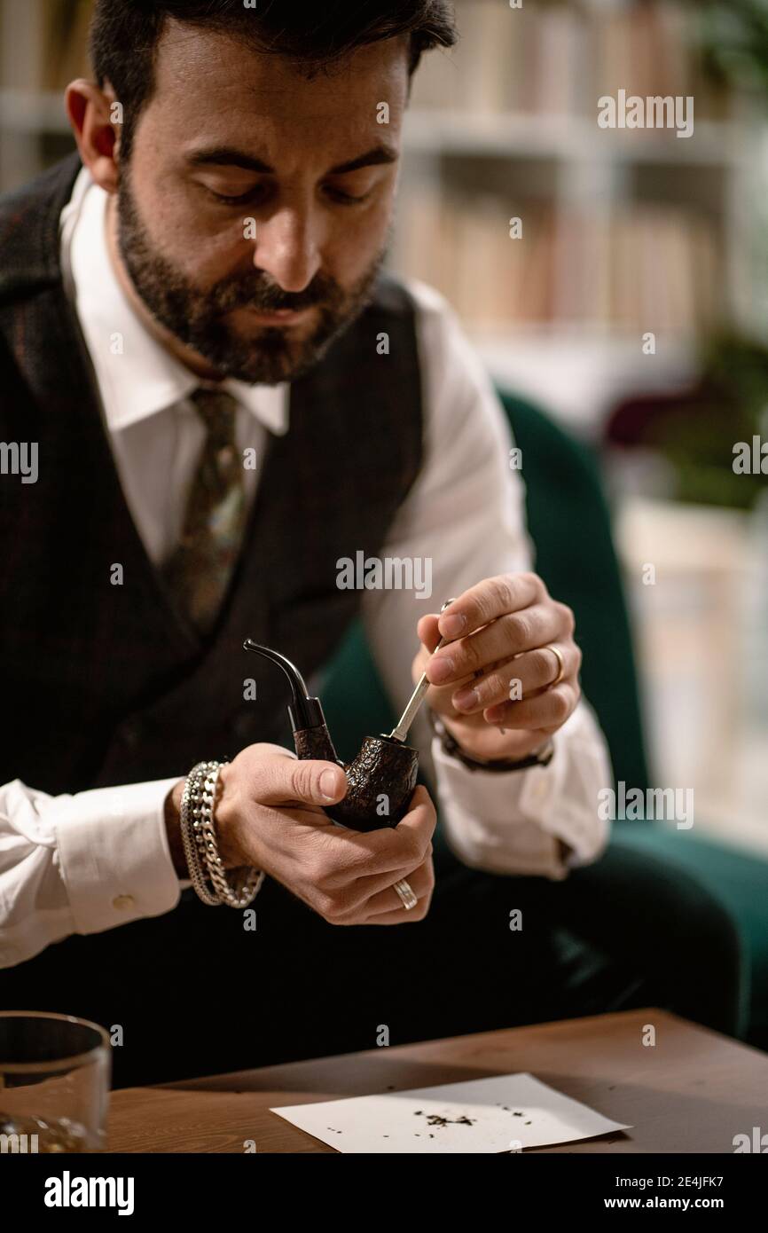 Homme barbu préparant une pipe à fumer Banque D'Images
