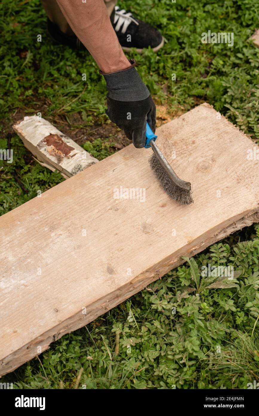 Mains de l'homme brossant la planche avec la brosse métallique Banque D'Images